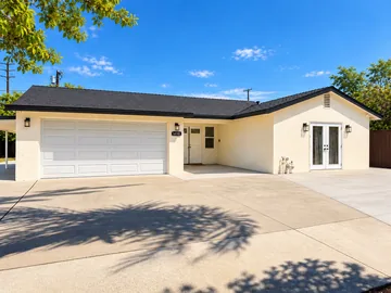 Front of Caring Corner, a single-story home in Arleta with a wide driveway and French doors