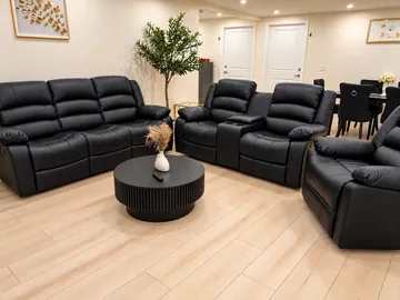 Living room with black leather recliner sofas around a round coffee table