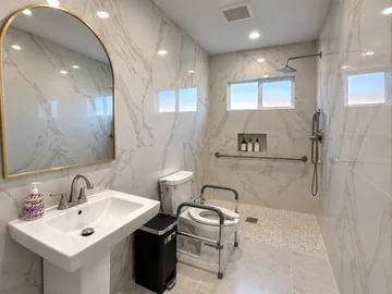 Accessible bathroom with a roll-in shower, grab bars and a toilet safety frame