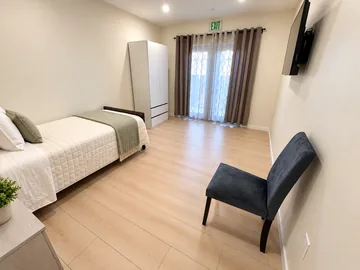 Bedroom with a single bed, armchair, wardrobe and French doors