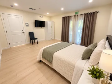 Spacious bedroom with French doors, a wardrobe and wall TV