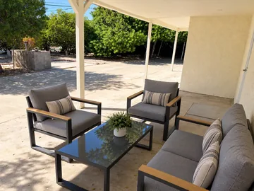 Covered patio lounge with cushioned outdoor chairs and a sofa