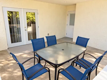 Covered patio dining table with blue chairs beside French doors